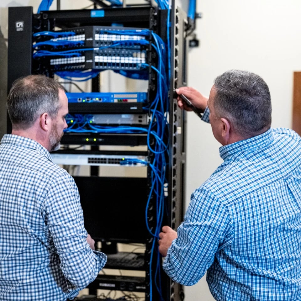 Technicians reviewing structured cabling in a network rack